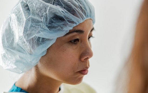 Close up on a hospital pharmacist's face with scrubs and hair covered