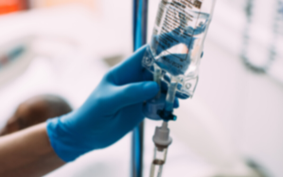 A nurse holds a bag of Baxter product.