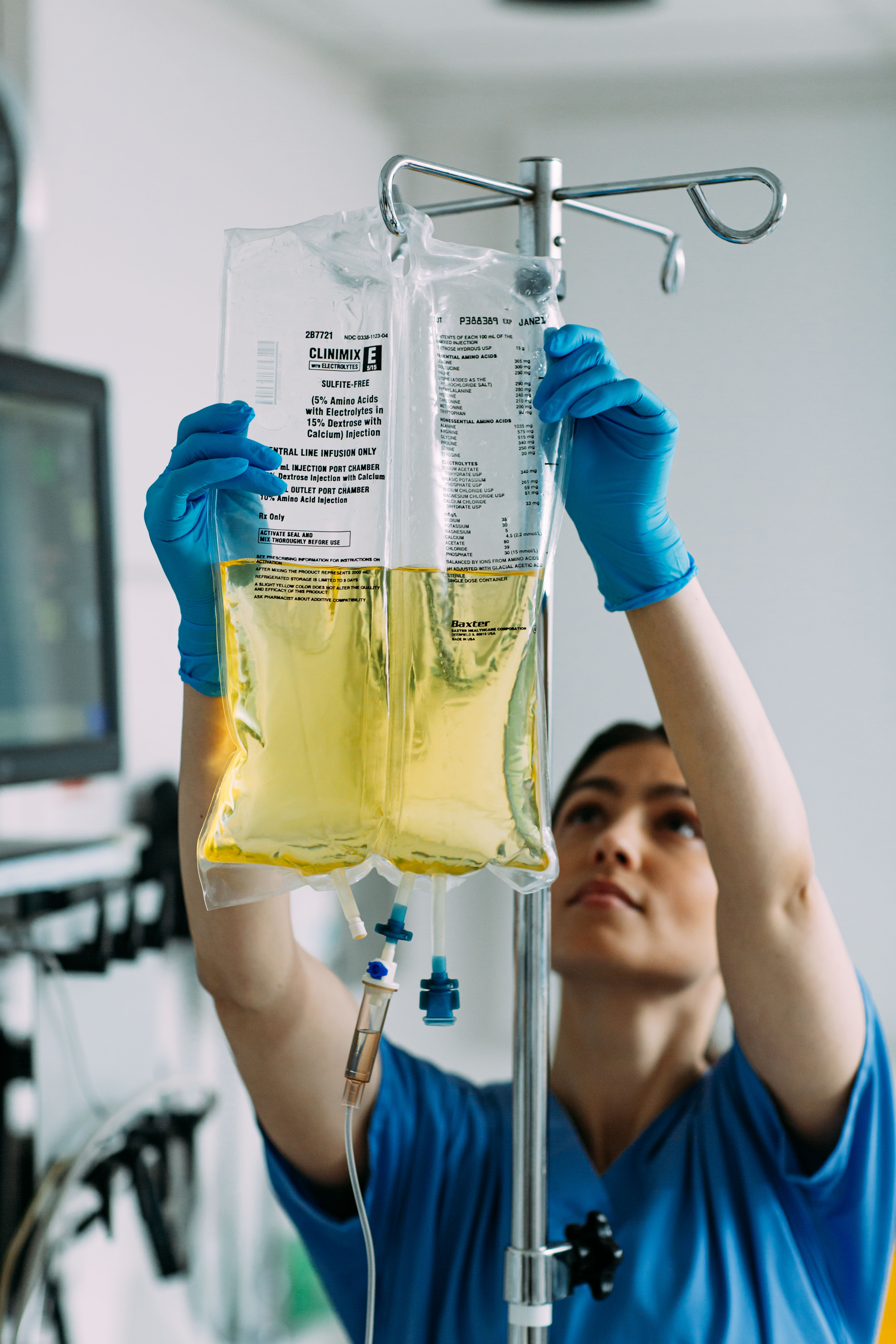 A nurse hangs a bag of Clinimix E for a patient who is receiving parenteral nutrition (PN)