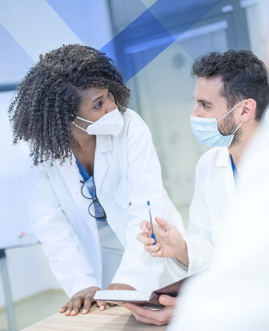 Healthcare professionals wearing masks have a discussion around a conference table