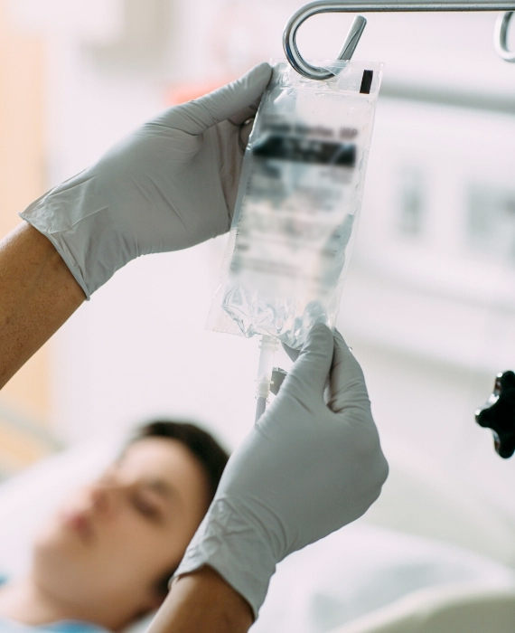 A nurse holds a bag fluid hanging from an IV pole