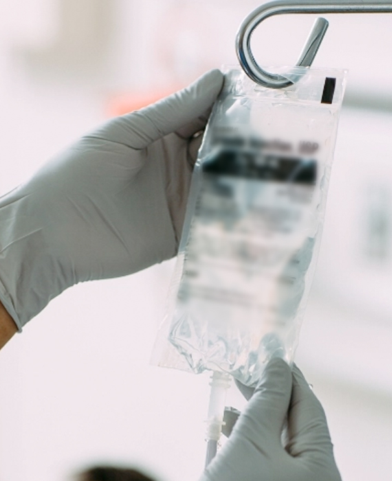 A nurse holds a bag fluid hanging from an IV pole