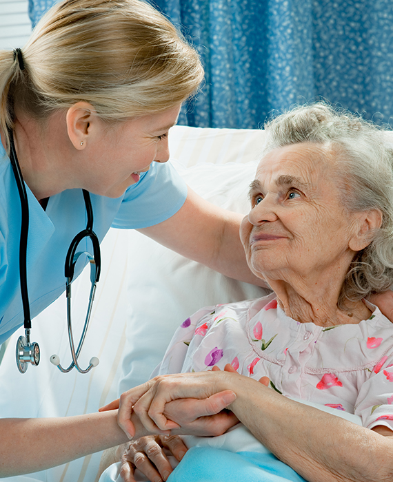 a nurse smiles while caring for an elderly patient