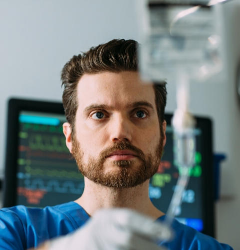 A nurse looks at a Baxter premixed medication on an IV pole