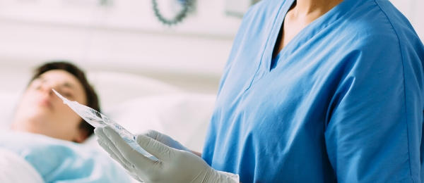 A nurse holds a Baxter premixed medication bag in her hands at a patient bedside